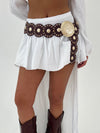 White skirt with decorative belt and brown boots on a plain background