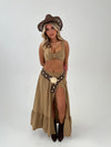 woman in a camel outfit with brown boots, belt and hat on a white background
