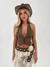 Woman wearing a brown halter top, beige pants, and a decorative belt with a white background