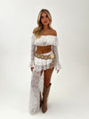 Woman wearing a white lace outfit with gold accents on a white background