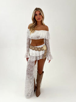 Woman wearing a white lace outfit with gold accents on a white background