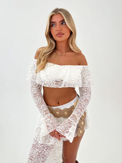 Lady in white top and skirt with a beige belt on a white background