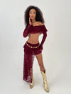 Lady wearing a burgundy outfit and gold belt and boots on a white background