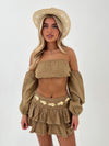 Woman wearing a camel outfit with a matching hat on a white background