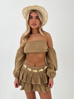 Woman wearing a camel outfit with a matching hat on a white background