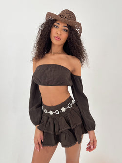 Woman wearing a brown outfit with a matching cowboy hat on a white background