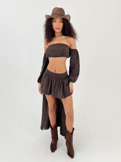 Woman wearing a brown outfit with a hat and boots on a white background