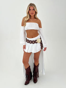 woman in white outfit with burgundy belt and boots