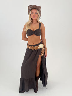 women in a brown outfit with hat belt and boots on a white background