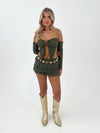 Woman wearing a green outfit with gold boots on a white background