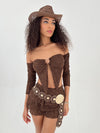 Woman wearing a brown outfit with long sleeves and a hat on a white background