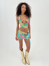 Woman wearing a colorful tie-dye outfit with gold boots on a white background