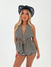 Woman wearing a black and white striped outfit with a black hat on a white background