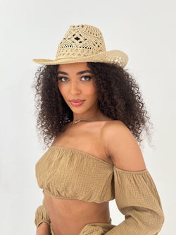 Woman wearing a straw hat and beige top on a white background