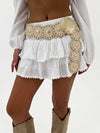 White skirt with gold embellishments and beige boots on a plain background